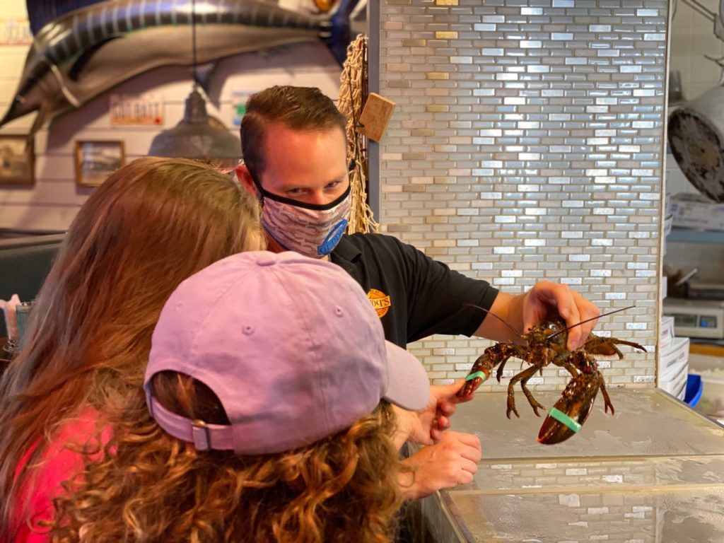 Geddy's in Bar Harbor, Maine, famous for its fresh Maine lobster, made to order straight from the live tank. Server with live lobster, showing guests.