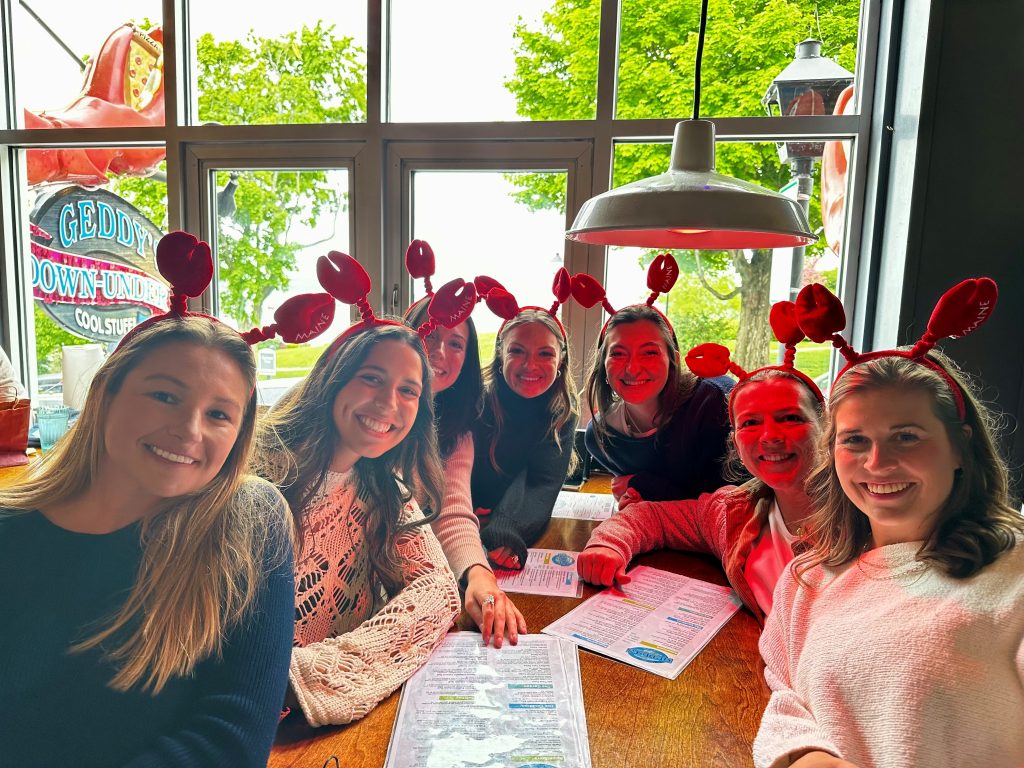 Friends wearing lobster headbands and enjoying a meal together at Geddy's in Bar Harbor, Maine.